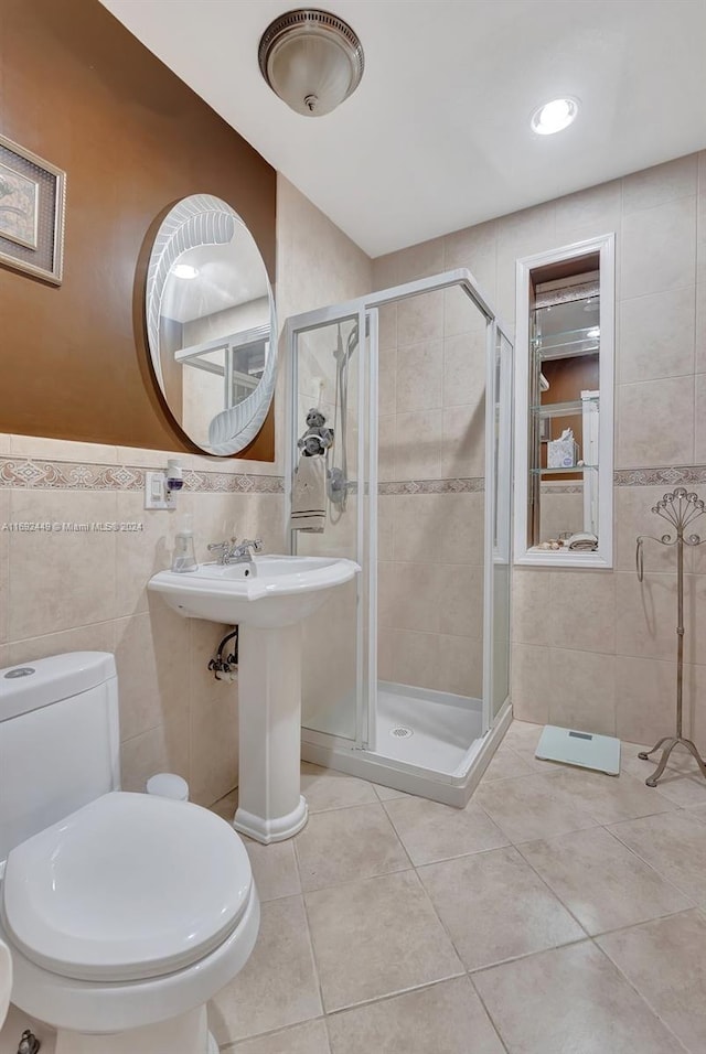 bathroom with tile patterned floors, a shower with door, tile walls, and toilet