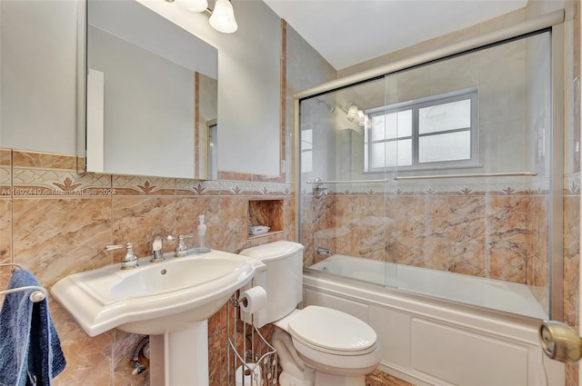 bathroom featuring toilet, tile walls, and combined bath / shower with glass door