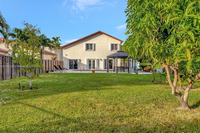 back of property with a gazebo and a lawn