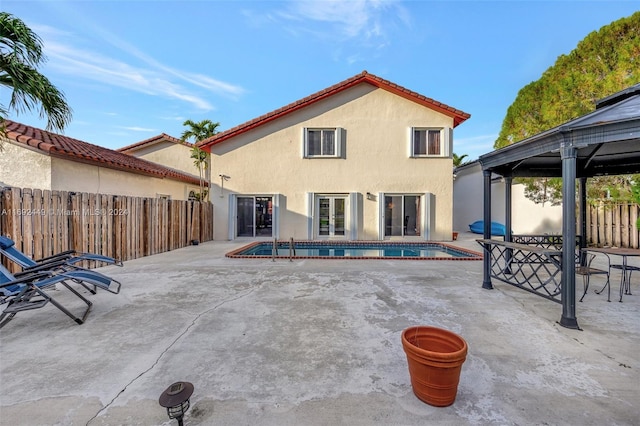 rear view of house featuring a gazebo, a patio, and a fenced in pool