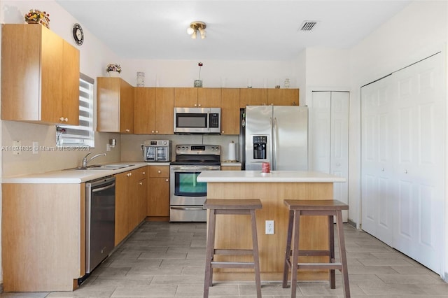 kitchen featuring a kitchen breakfast bar, a center island, sink, and appliances with stainless steel finishes