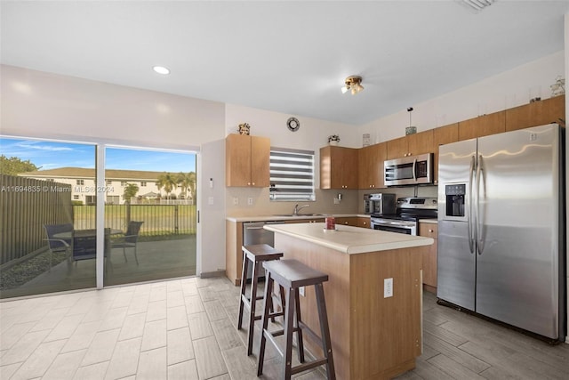 kitchen with sink, stainless steel appliances, a kitchen breakfast bar, a kitchen island, and light wood-type flooring