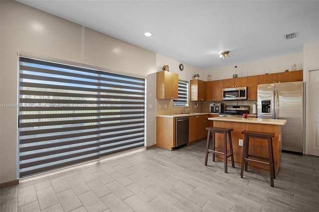 kitchen featuring a breakfast bar, sink, light hardwood / wood-style flooring, a kitchen island, and stainless steel appliances