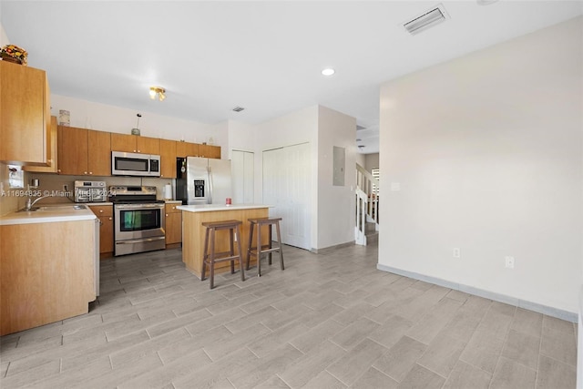 kitchen with sink, a center island, light hardwood / wood-style floors, a breakfast bar area, and appliances with stainless steel finishes