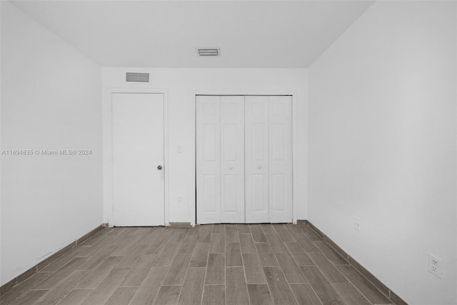 unfurnished bedroom featuring wood-type flooring and a closet