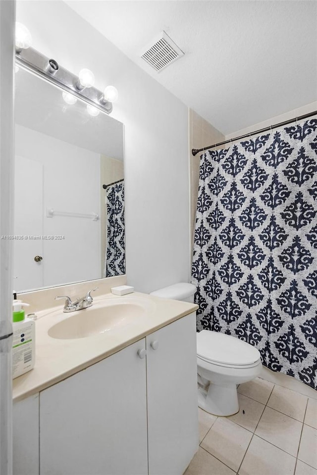 bathroom with tile patterned flooring, vanity, toilet, and curtained shower