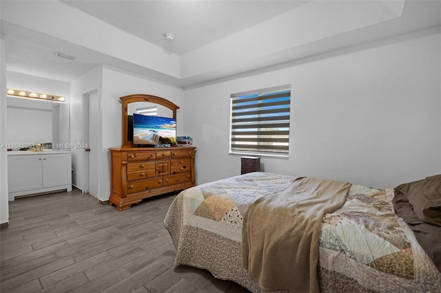 bedroom with ensuite bath and light wood-type flooring