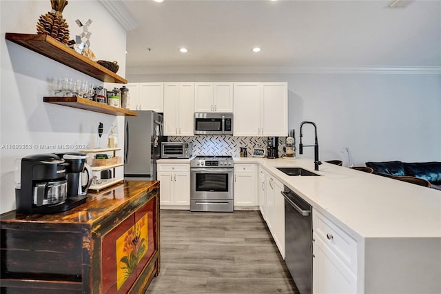 kitchen with hardwood / wood-style floors, white cabinets, sink, appliances with stainless steel finishes, and kitchen peninsula