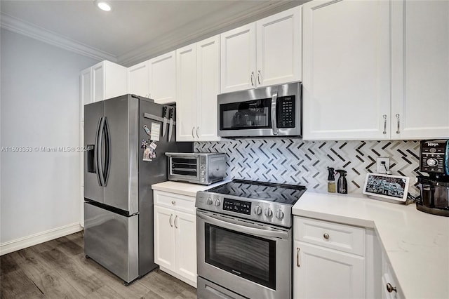 kitchen featuring appliances with stainless steel finishes, white cabinetry, ornamental molding, and wood-type flooring