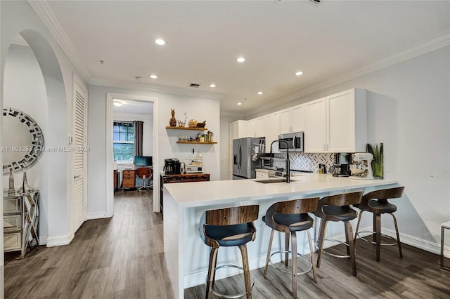 kitchen with kitchen peninsula, appliances with stainless steel finishes, dark hardwood / wood-style floors, and white cabinetry