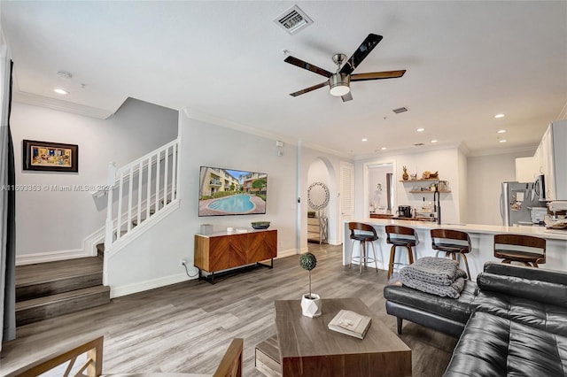 living room featuring hardwood / wood-style flooring, ceiling fan, and crown molding