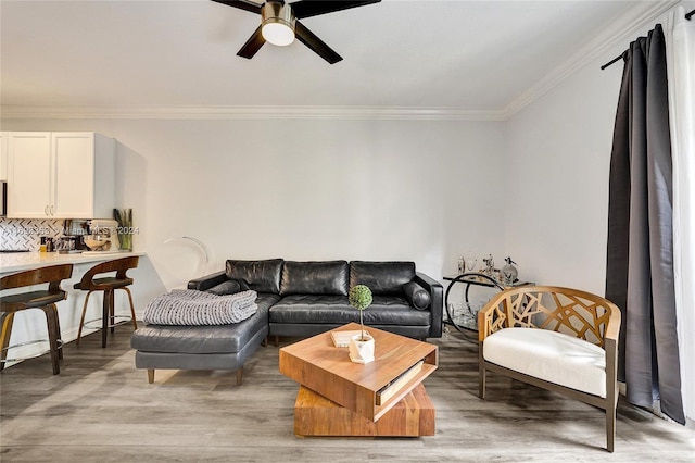 living room featuring light hardwood / wood-style floors, ceiling fan, and crown molding