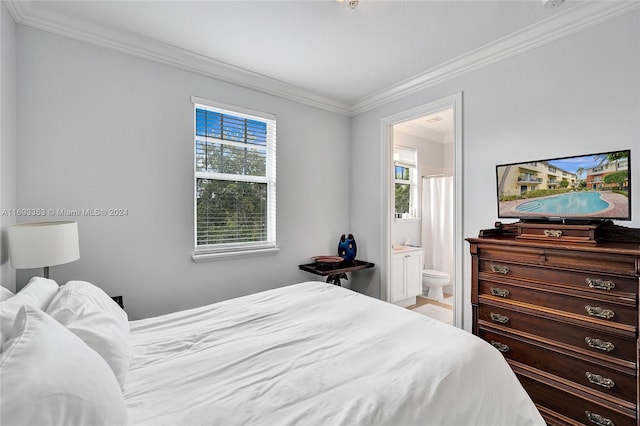 bedroom featuring ensuite bath, multiple windows, and ornamental molding