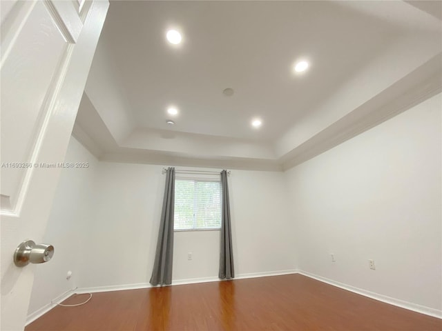 unfurnished room featuring wood-type flooring and a tray ceiling