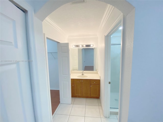 bathroom featuring vanity, tile patterned flooring, a shower with door, and ornamental molding