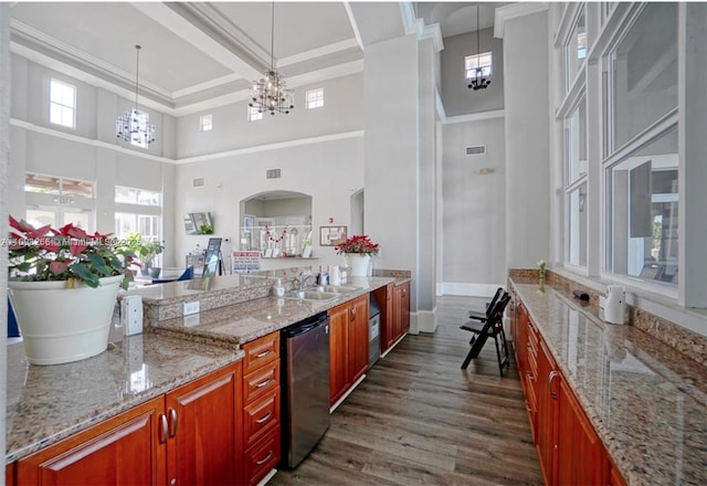 kitchen featuring an inviting chandelier, dark hardwood / wood-style floors, a towering ceiling, dishwasher, and light stone counters