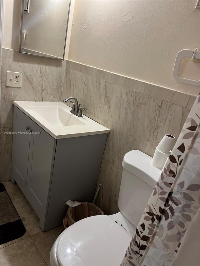 bathroom with vanity, a shower with curtain, tile patterned flooring, toilet, and tile walls