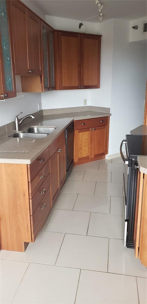 kitchen with sink, light tile patterned floors, stove, and black dishwasher