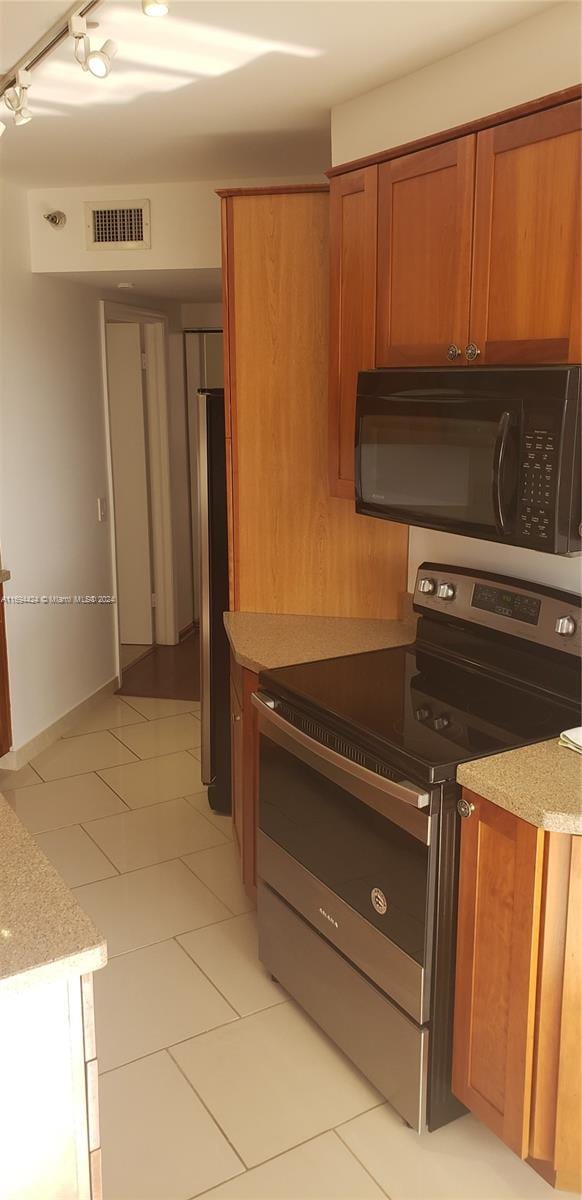 kitchen featuring light tile patterned flooring, track lighting, and appliances with stainless steel finishes