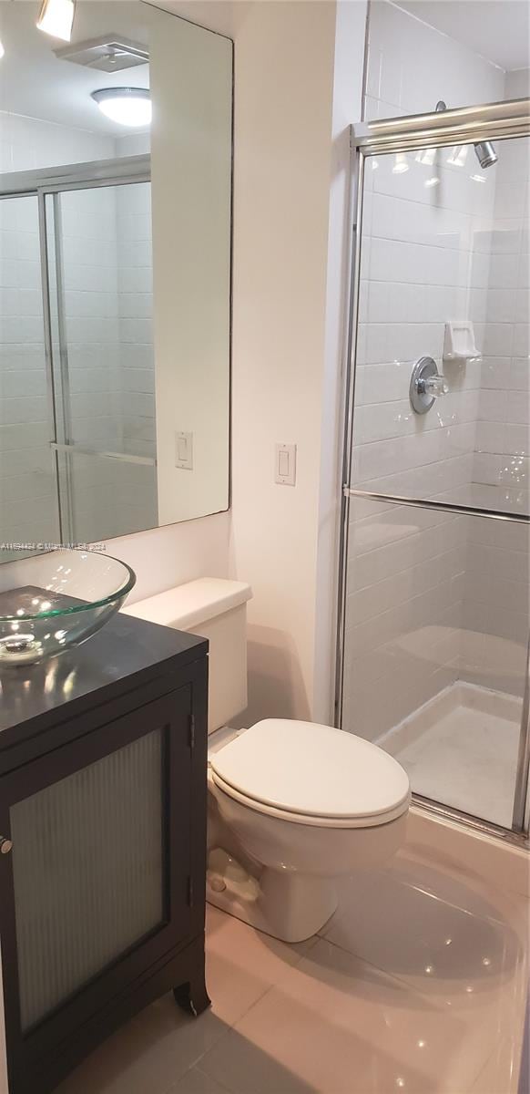 bathroom featuring toilet, vanity, tile patterned floors, and walk in shower