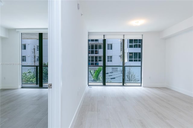 spare room featuring light hardwood / wood-style flooring and a wall of windows