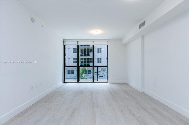 spare room featuring expansive windows and light hardwood / wood-style flooring