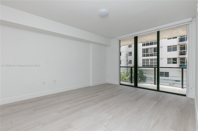 empty room with expansive windows and light wood-type flooring