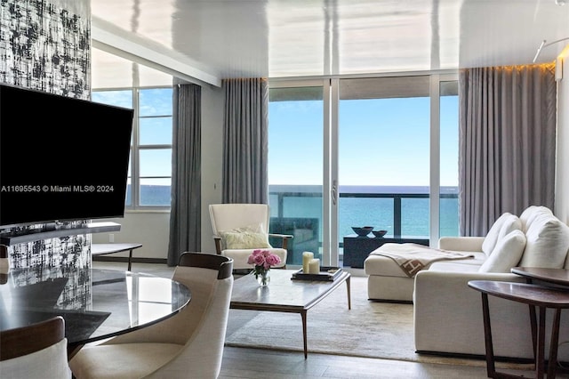 living room with expansive windows, a water view, a healthy amount of sunlight, and hardwood / wood-style flooring