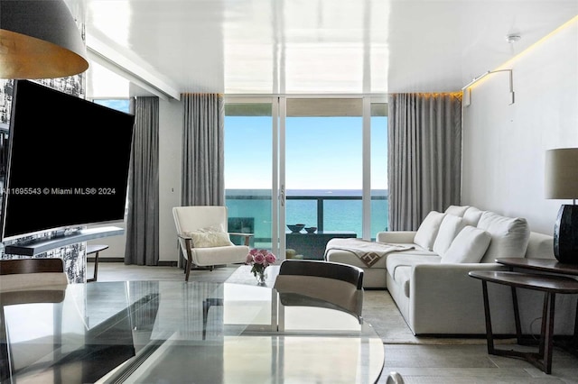 living room with a healthy amount of sunlight, a water view, and a wall of windows