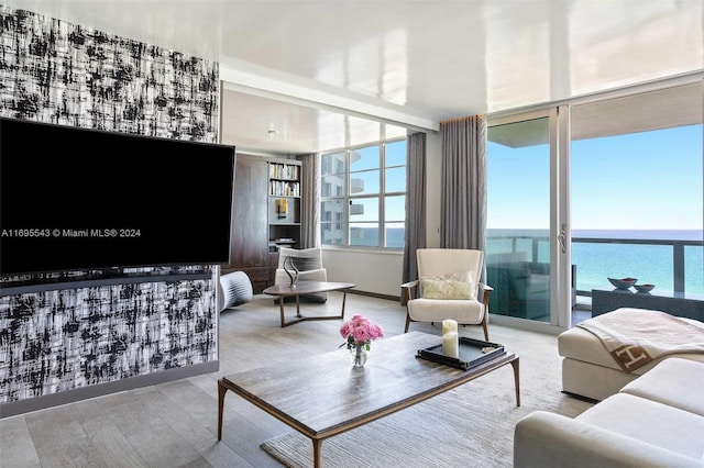 living room with expansive windows, a water view, and light hardwood / wood-style floors