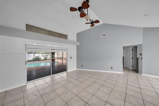 tiled spare room with ceiling fan and high vaulted ceiling