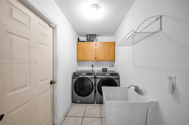 clothes washing area with separate washer and dryer, sink, light tile patterned flooring, and cabinets