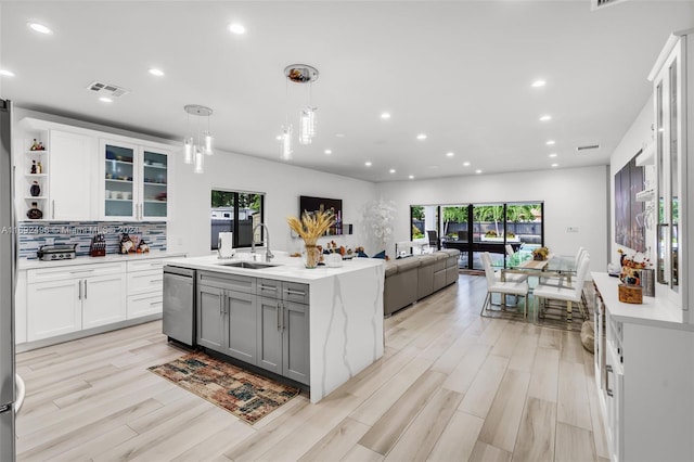 kitchen featuring white cabinets, pendant lighting, sink, and light hardwood / wood-style flooring