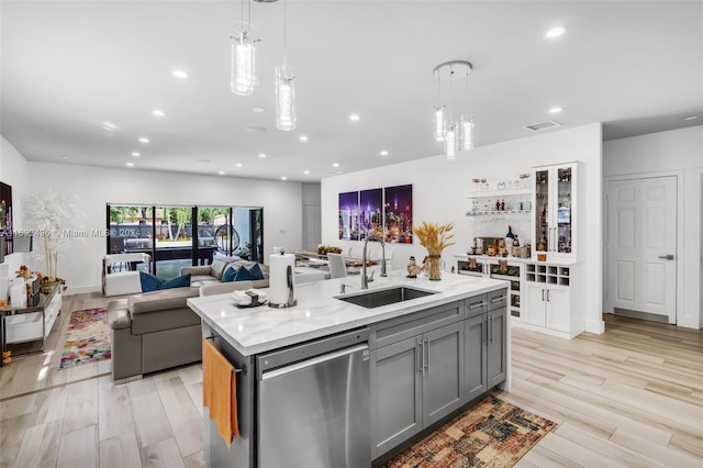 kitchen with gray cabinetry, dishwasher, a center island with sink, decorative light fixtures, and light hardwood / wood-style floors