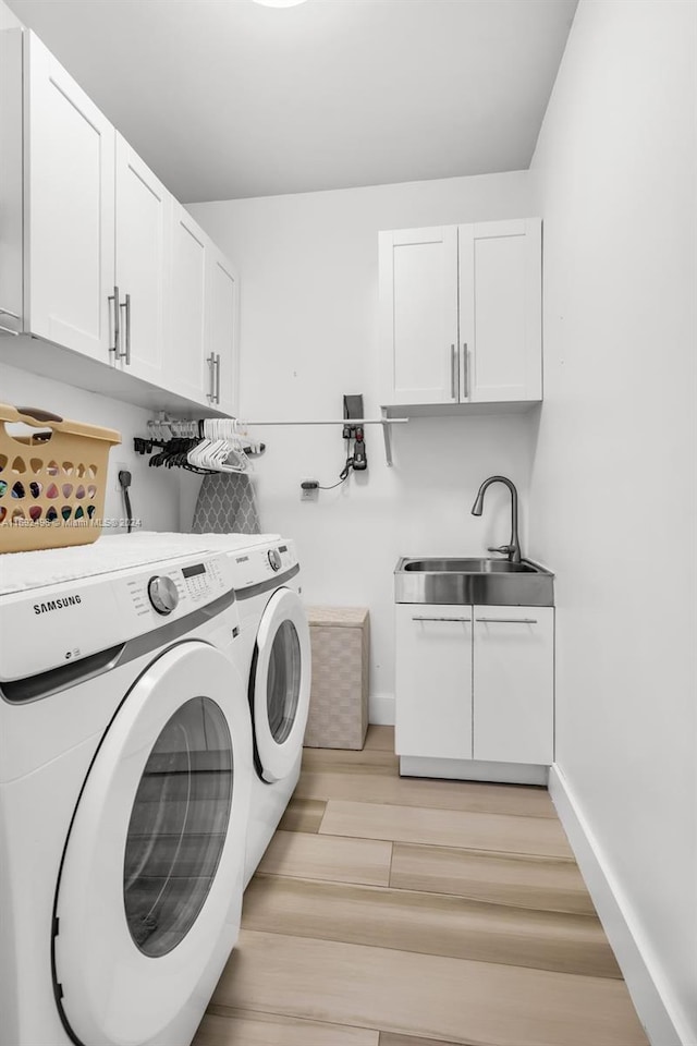 washroom with cabinets, light hardwood / wood-style flooring, washer and clothes dryer, and sink