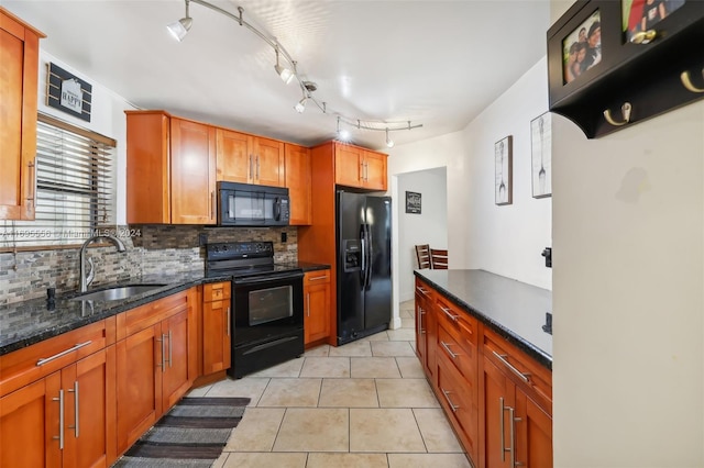 kitchen featuring dark stone counters, black appliances, sink, tasteful backsplash, and light tile patterned flooring