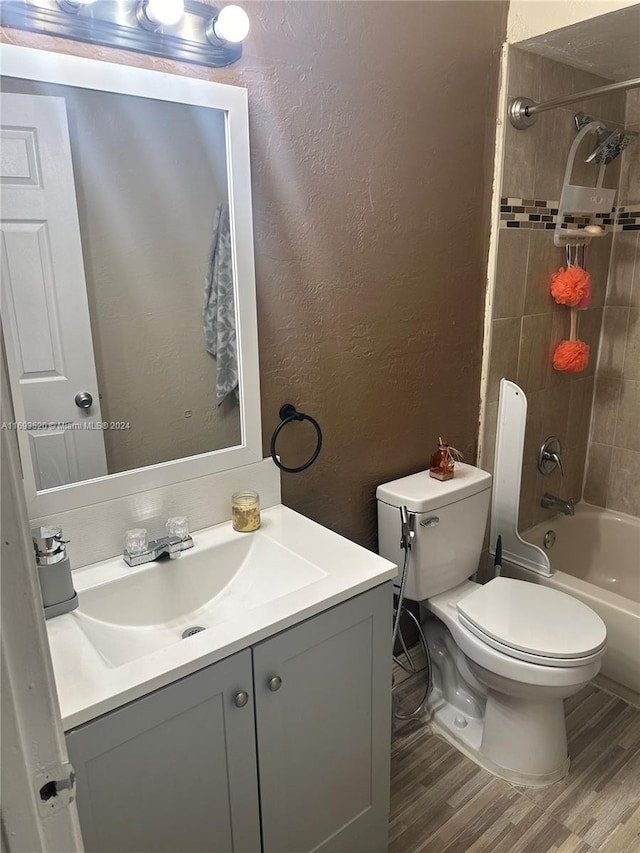 full bathroom featuring vanity, hardwood / wood-style flooring, toilet, and tiled shower / bath