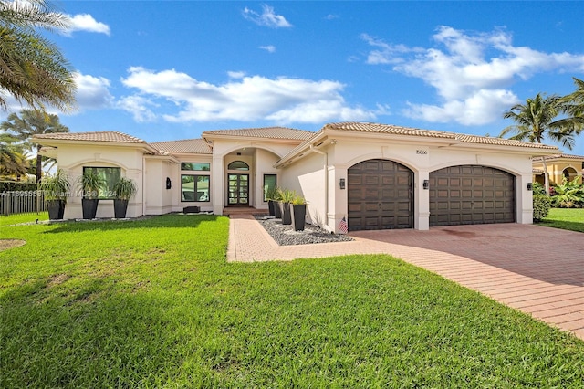 mediterranean / spanish house featuring a garage and a front lawn