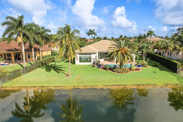 back of property with a lawn and a water view