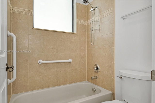 bathroom with toilet and tiled shower / bath