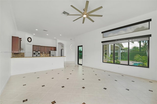 unfurnished living room with crown molding, light tile patterned flooring, and ceiling fan