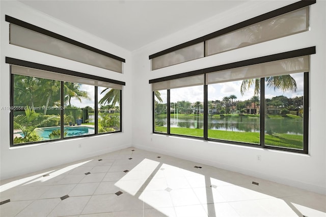 empty room with a water view, light tile patterned floors, and a wealth of natural light