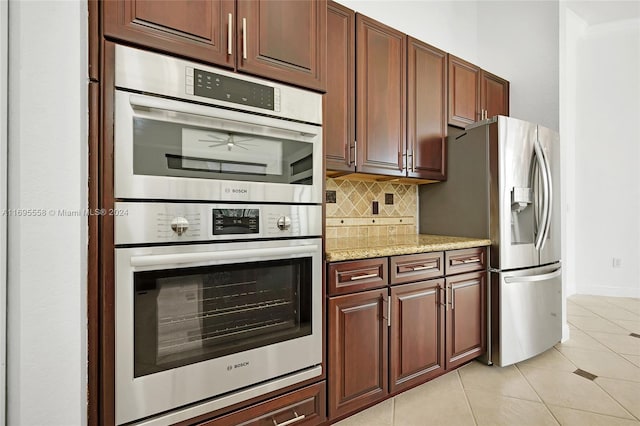 kitchen featuring decorative backsplash, light tile patterned flooring, light stone counters, and appliances with stainless steel finishes