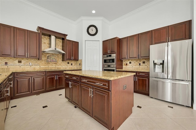 kitchen featuring a center island, wall chimney exhaust hood, light stone countertops, light tile patterned flooring, and stainless steel appliances