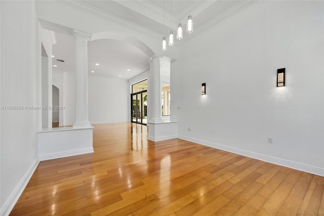 unfurnished living room with light wood-type flooring, ornamental molding, and a towering ceiling