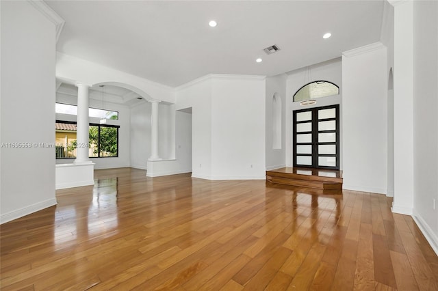 interior space featuring decorative columns, ornamental molding, and light wood-type flooring