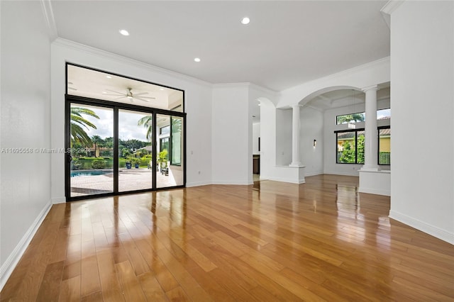 spare room with hardwood / wood-style floors, ceiling fan, crown molding, and decorative columns