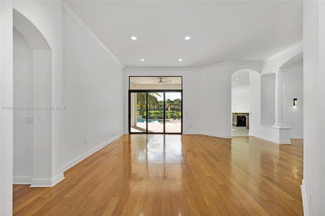 unfurnished living room featuring ornate columns, crown molding, and light hardwood / wood-style floors