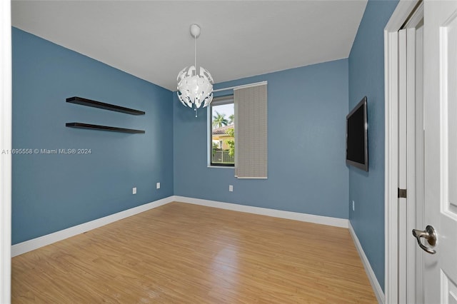 spare room featuring hardwood / wood-style flooring and a chandelier