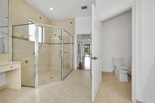 bathroom with tile patterned flooring, toilet, and a shower with door